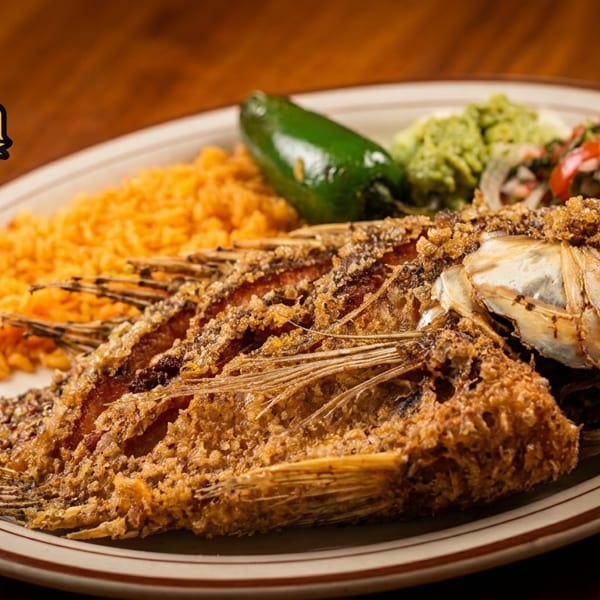 Whole fried fish with rice, jalapeño, guacamole, and pico de gallo on a plate.